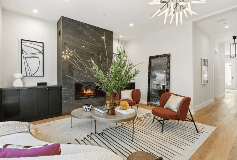 Hermosa sala de estar moderna con chimenea de mármol negro, muebles elegantes y decoración contemporánea, ideal para comprar o alquilar propiedades de lujo en la mejor zona.