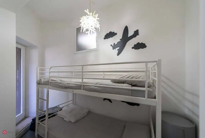 Cama litera en habitación moderna con decoración infantil en color blanco y detalles en negro, ideal para viviendas en venta o alquiler.