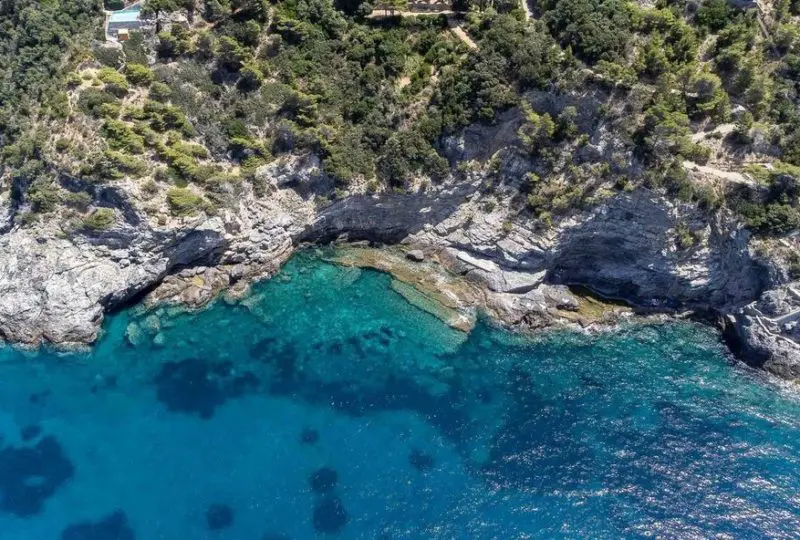 Vistas aéreas de un acantilado con vegetación y aguas cristalinas en la costa, ideal para propiedades exclusivas en la naturaleza.