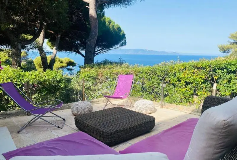 Vista panorámica del mar desde terraza con muebles de exterior, vegetación y árboles, ideal para propiedades en venta o alquiler en zonas cercanas a la costa en España.