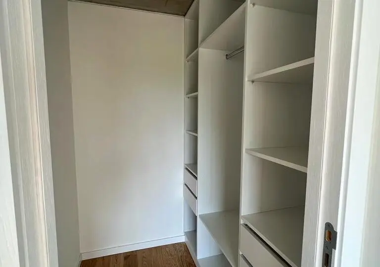 Closet empotrado en una propiedad moderna, ideal para organizar ropa y accesorios en el hogar. Dispone de estantes y cajones para optimizar el espacio de almacenamiento.