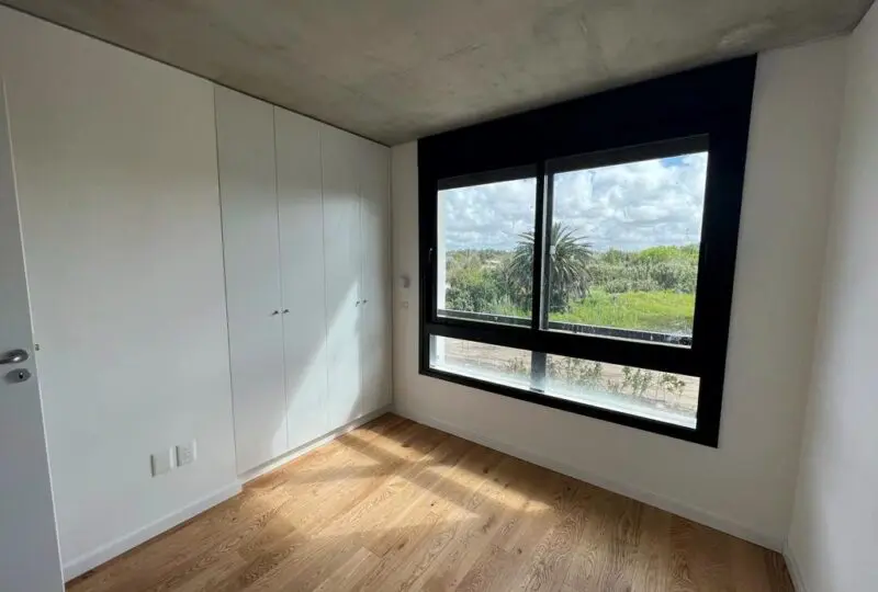 Amplio dormitorio con vista panorámica a la naturaleza, ventanas grandes y armario empotrado, ideal para vivienda moderna en Horus Real Estate Agency.