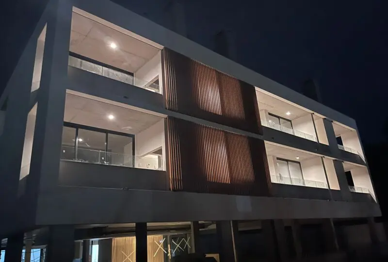 Moderno edificio residencial con diseño arquitectónico vanguardista en urbanización exclusiva, iluminación nocturna que resalta sus elegantes líneas y fachada moderna.