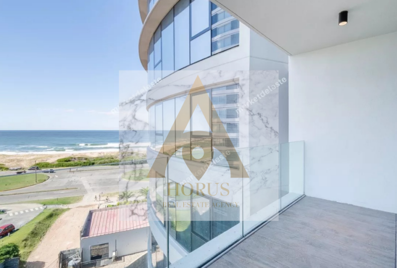 Vistas al océano desde un balcón moderno en un edificio de lujo, propiedad de la Agencia Inmobiliaria Horus en la costa, ideal para comprar o alquilar apartamentos frente al mar en ubicación privilegiada.