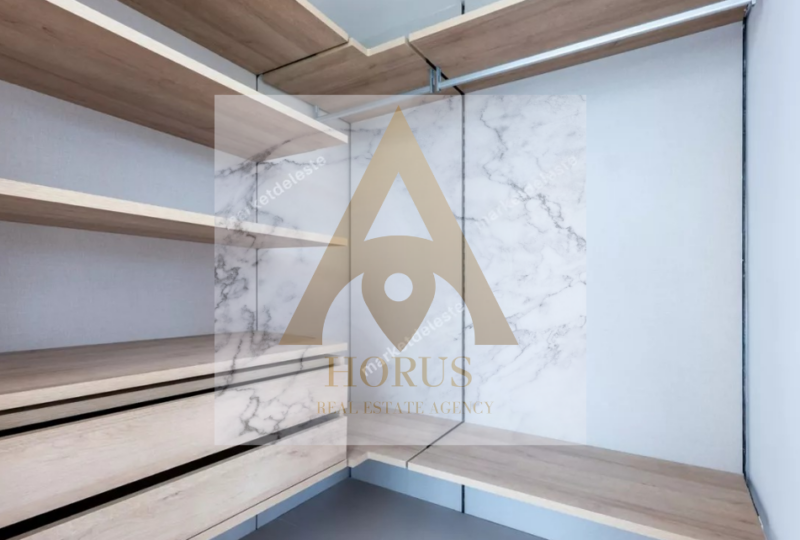 Armario empotrado con estanterías de madera, acabado en mármol blanco y diseño moderno, ideal para viviendas en venta o alquiler en la zona de Horus Real Estate Agency.