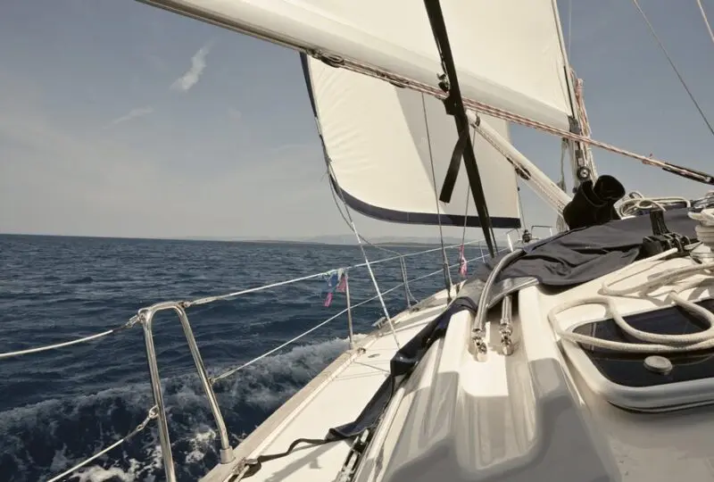 Vela en el mar, imagen de una embarcación deportiva, ideal para servicios inmobiliarios de lujo y propiedades frente al mar, destacando la vida en la costa y opciones exclusivas en bienes raíces marítimos.