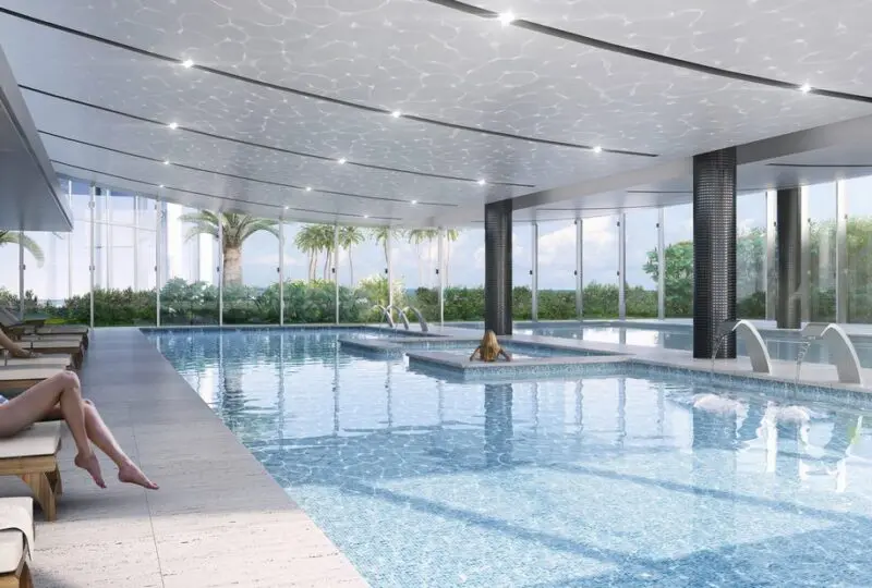 Piscina cubierta en complejo de lujo con vidrios panorámicos, zona de relax y vista al exterior, ideal para inversión inmobiliaria y alquiler vacacional en zonas exclusivas.