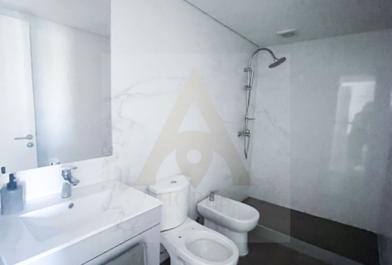 Baño moderno con ducha y sanitario en vivienda en alquiler, diseño elegante y funcional en inmobiliaria Horus Real Estate Agency.