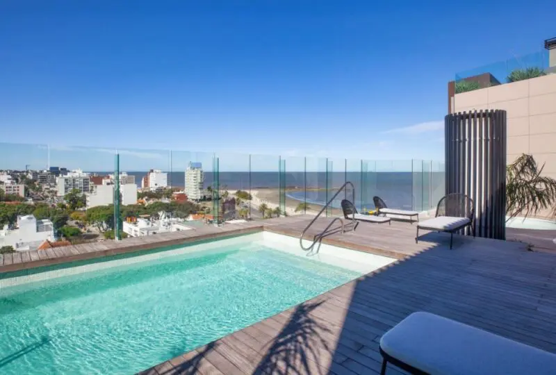 Vistas desde una terraza con piscina en edificio moderno en la ciudad costera, ideal para inversiones en bienes raíces y disfrutar de espacios exclusivos en la playa.