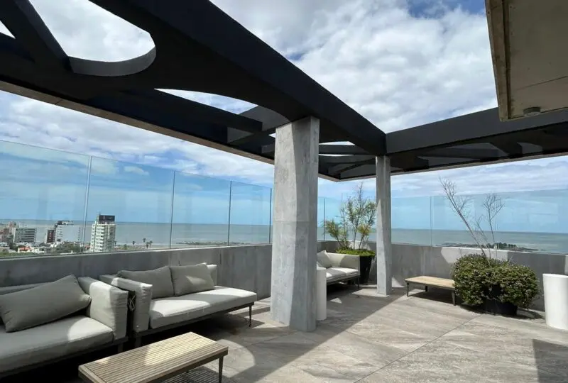 Vistas panorámicas al mar desde la azotea de la agencia inmobiliaria Horus, espacio moderno y elegante con zonas de descanso, ideal para invertir en propiedades frente al mar en la ciudad.