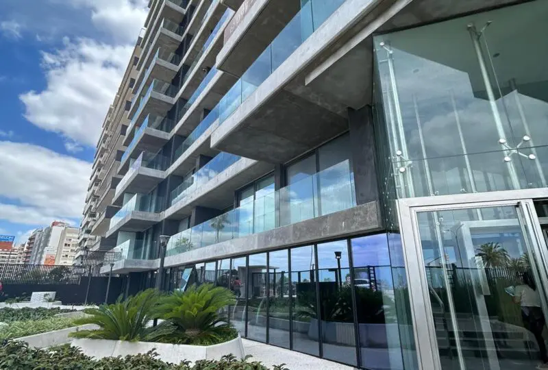 Horus Real Estate Agency moderna edificio residencial con amplios balcones y fachada de vidrio en zona urbana.