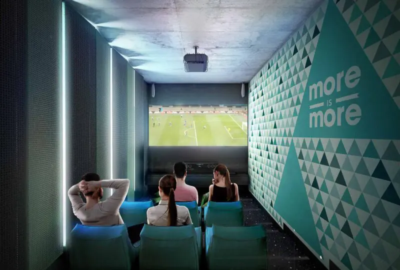 Vistas de la sala de cine en un espacio deportivo moderna con vista a un partido de fútbol en el estadio. Ideal para eventos deportivos y ocio, en un entorno cómodo y tecnológico.