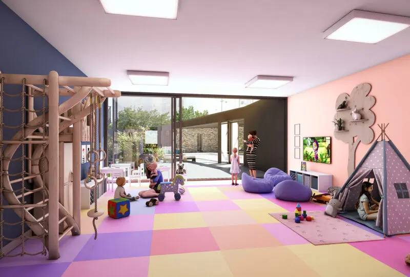 Juegos infantiles y zona de juego en un espacio de guardería o ludoteca moderna y luminosa, con mobiliario colorido, paredes decorativas y grandes ventanas que dejan entrar la luz natural.
