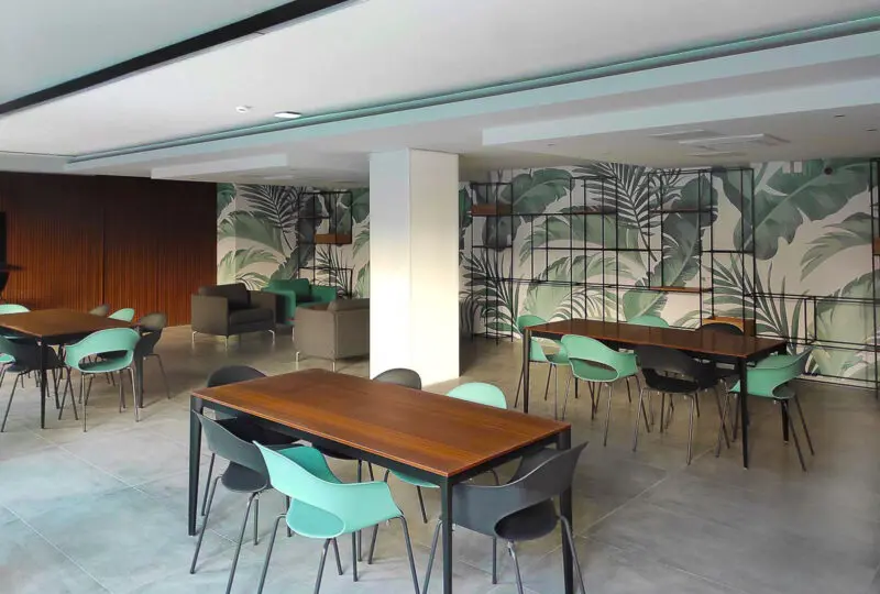 Amplio espacio interior de oficina moderna y elegante, ideal para inmobiliarias y agencias de bienes raíces. Diseño contemporáneo con murales de naturaleza y muebles funcionales.