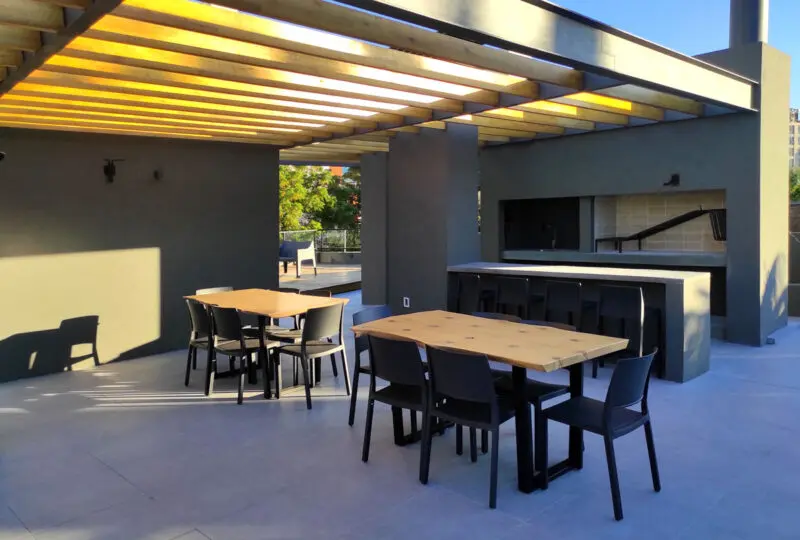 Amplia terraza con mobiliario moderno, ideal para eventos y reuniones, con zona de barbacoa y sombra, ubicada en un complejo residencial exclusivo en la ciudad.