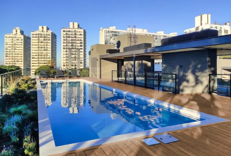 Piscina en azotea con vistas a edificios residenciales en la ciudad, espacio ideal para relajarse y disfrutar del entorno urbano.