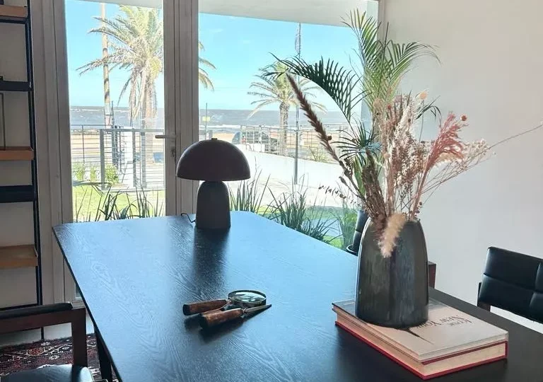 Mesas de oficina modernas con vistas al mar, ideales para espacios de trabajo en propiedades de lujo en Costa del Sol, Málaga y Marbella. Alfombra elegante y decoración contemporánea.