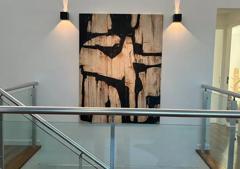 Puerta de entrada moderna en residencia de lujo con iluminación LED y pintura decorativa abstracta, ideal para venta de propiedades exclusivas en Horus Real Estate Agency.