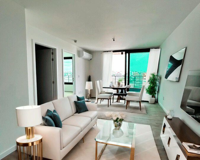 Moderno salón de apartamento en alquiler en Horus Inmobiliaria, con decoración elegante, sofá blanco, mesa de centro y terraza con vistas panorámicas, ideal para vivir en un entorno cómodo y sofisticado.